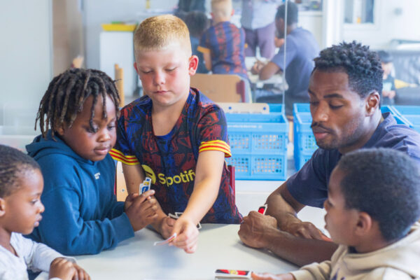 Kinderen en een pedagogisch medewerker aan tafel bij BSO Andromeda in Hoogezand